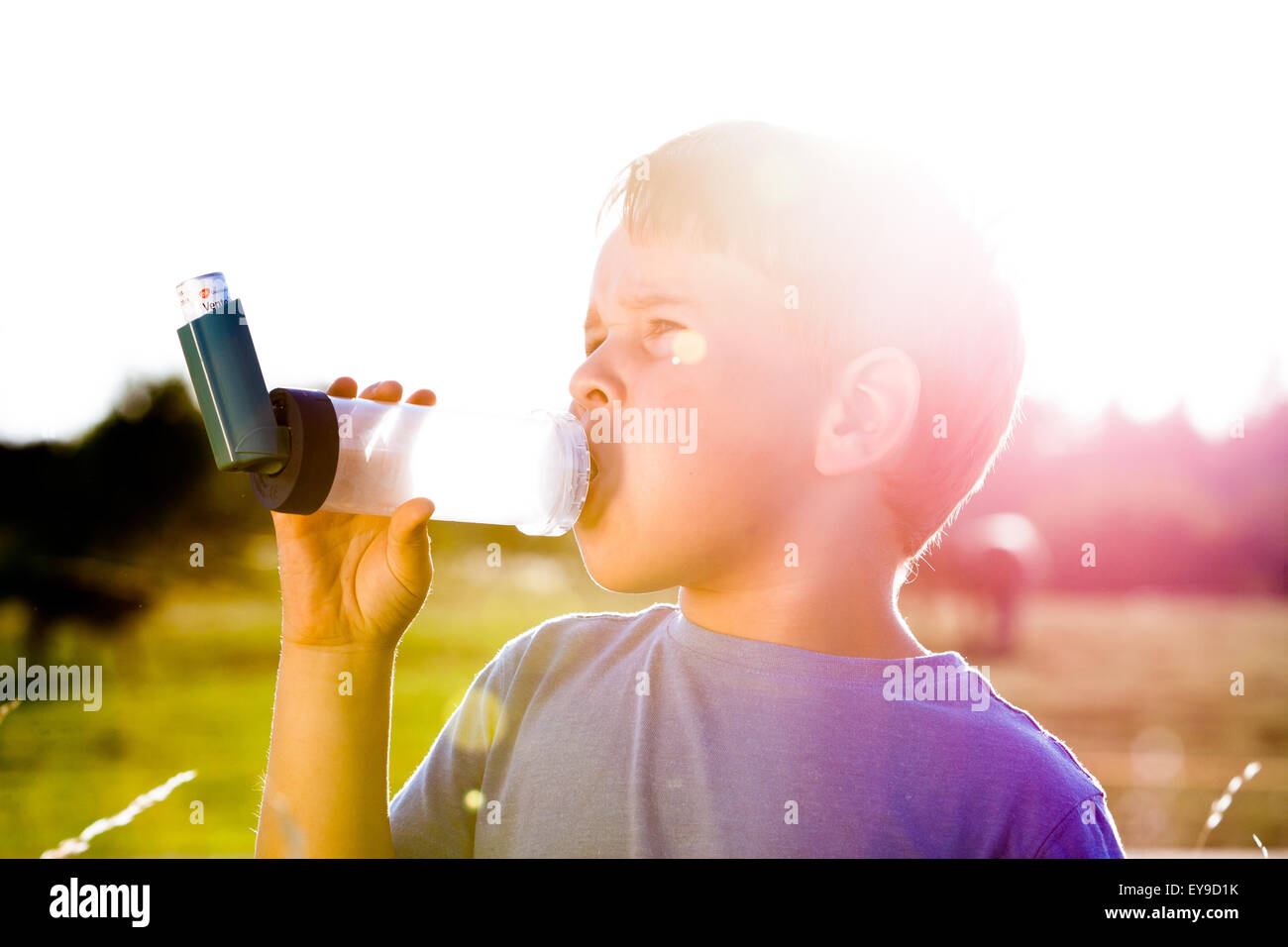 Boy using inhaler for asthma in village with summer sunset Stock Photo ...