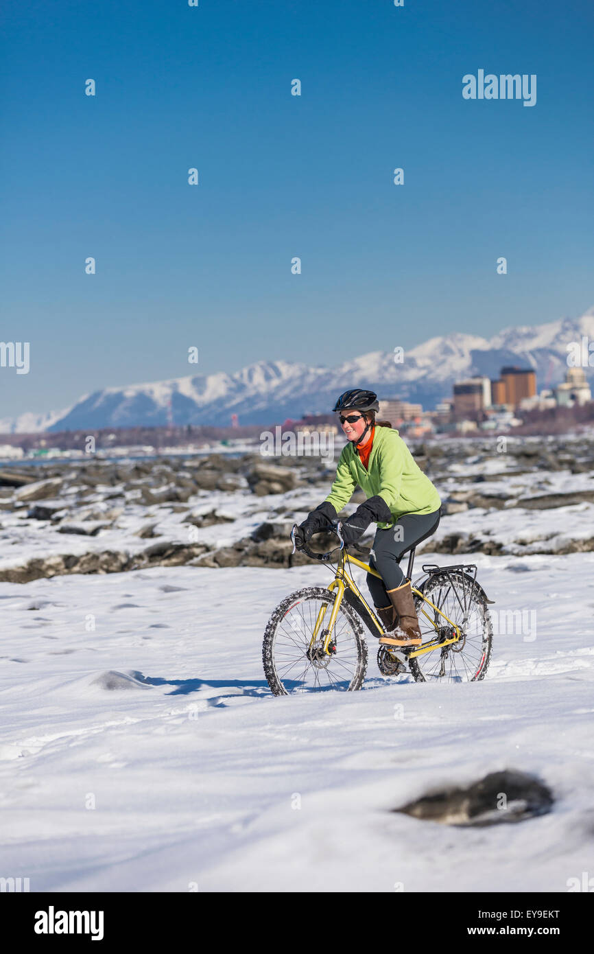 A young woman rides a studded tire bicycle next to the Tony Knowles