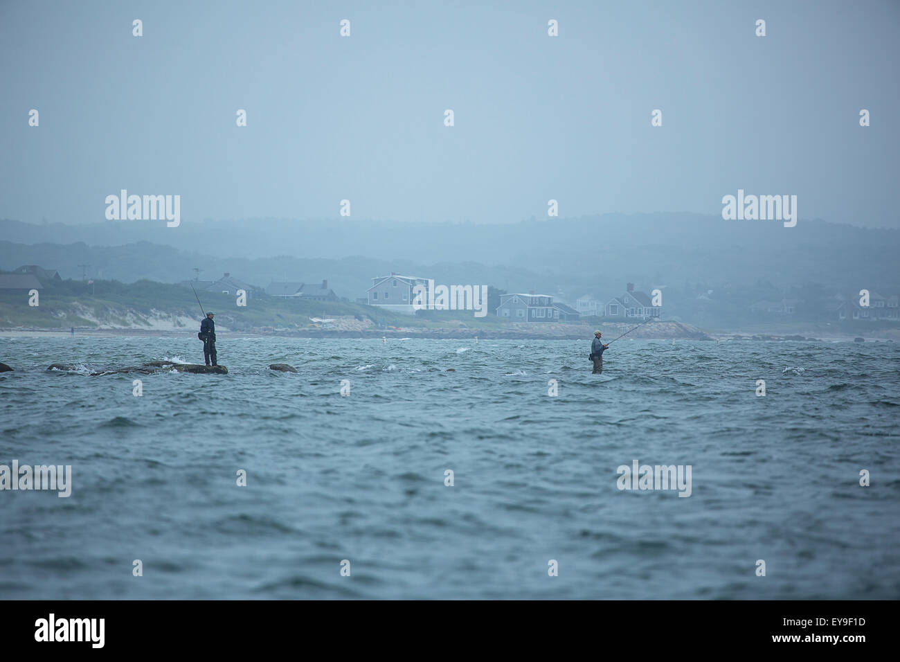 Fishing on the rocks in the water along the coast; Cape Cod ...