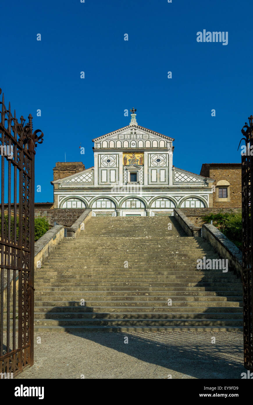 Exterior of San Miniato al Monte shot through an open gate at the foot of the steps. Florence, Italy. Stock Photo