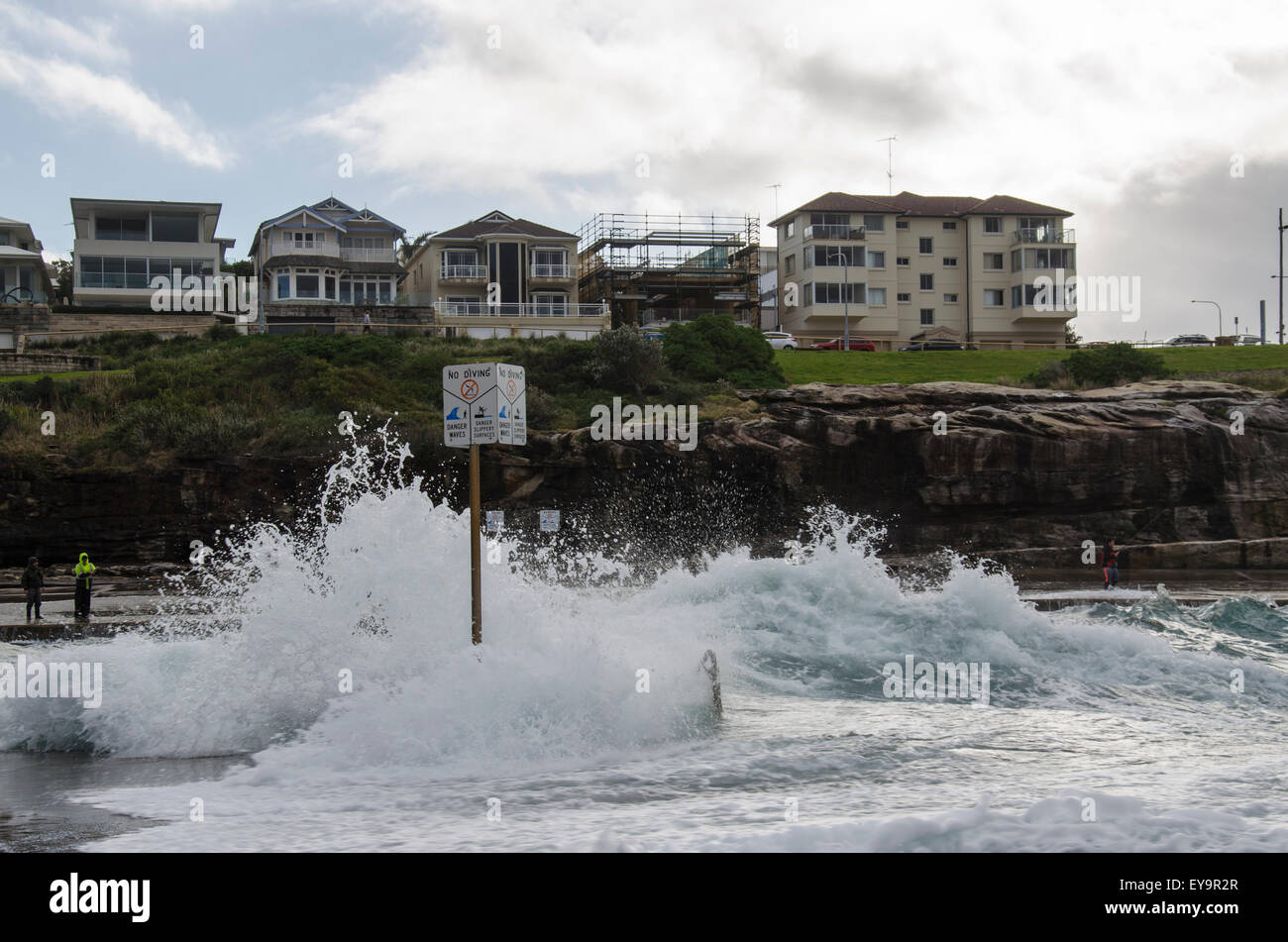 A large wave nearly covers a no diving sign at Clovelly Beach in Sydney, Australia during stormy weather Stock Photo