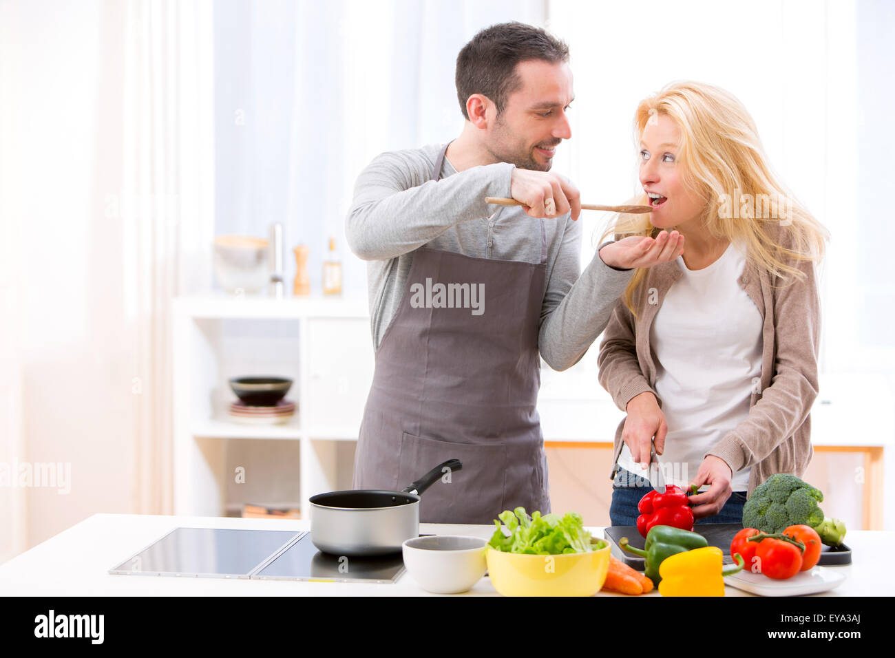 View of a Young attractive man give food to his wife to taste Stock Photo