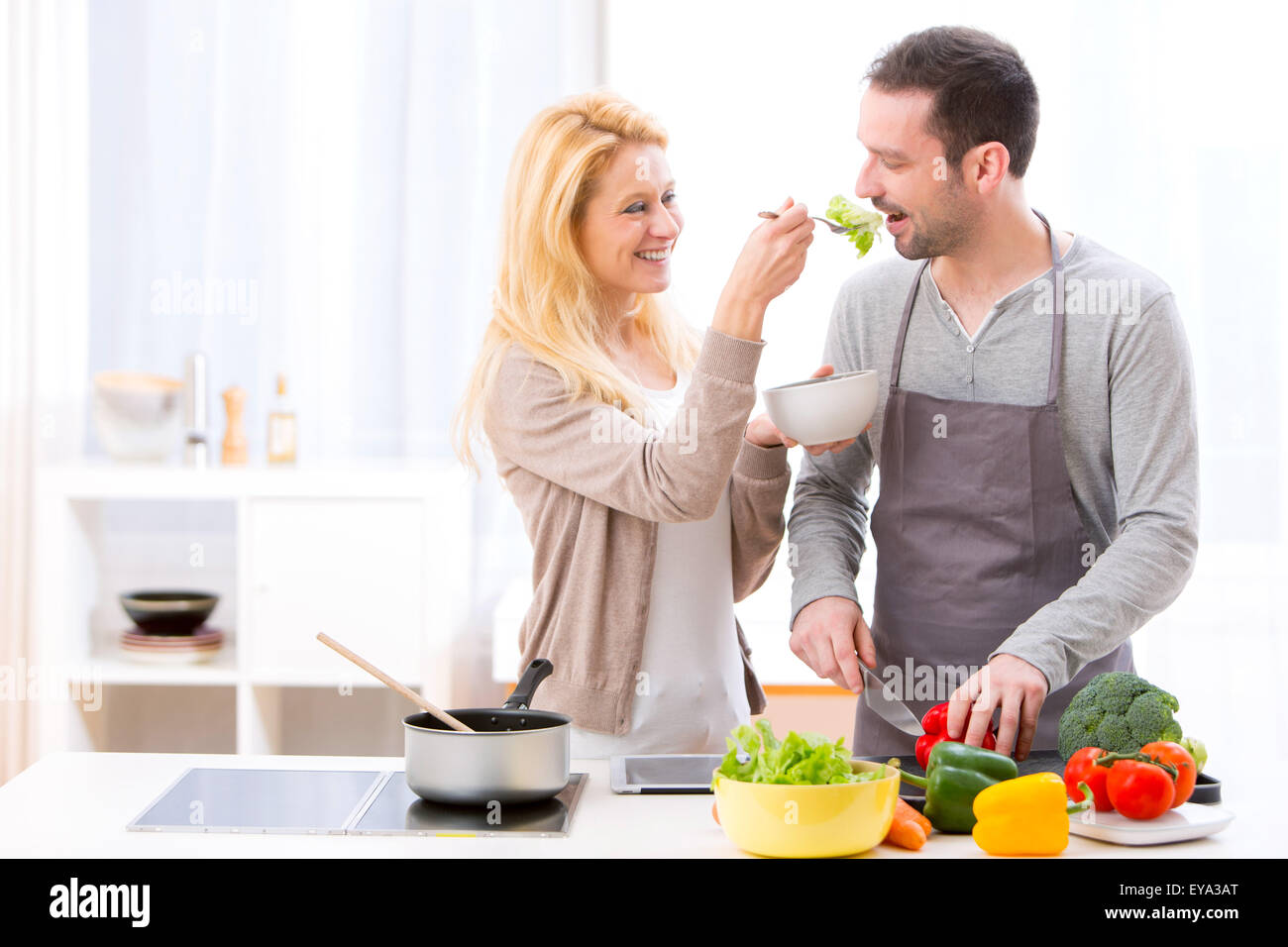 View of a Young attractive woman give food to her husband to taste Stock Photo