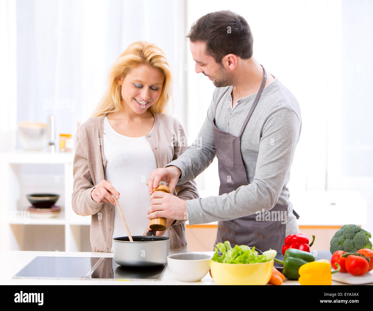 View of a Young attractive man helping out his wife while cooking Stock Photo