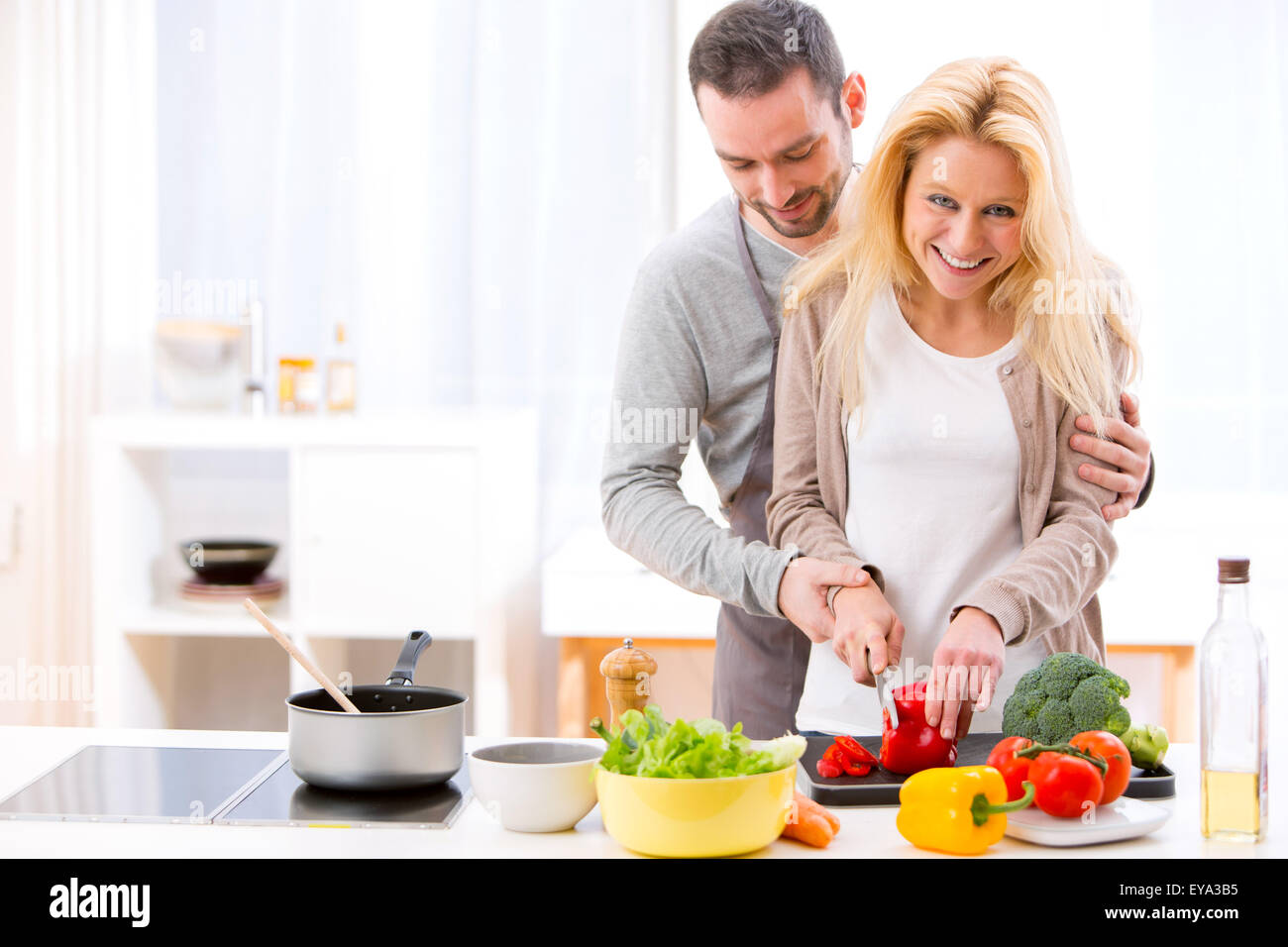 View of a Young attractive man helping out his wife while cooking Stock Photo