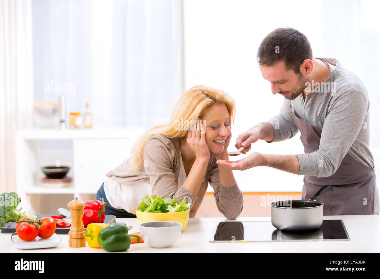 View of a Young attractive woman give food to her husband to taste Stock Photo