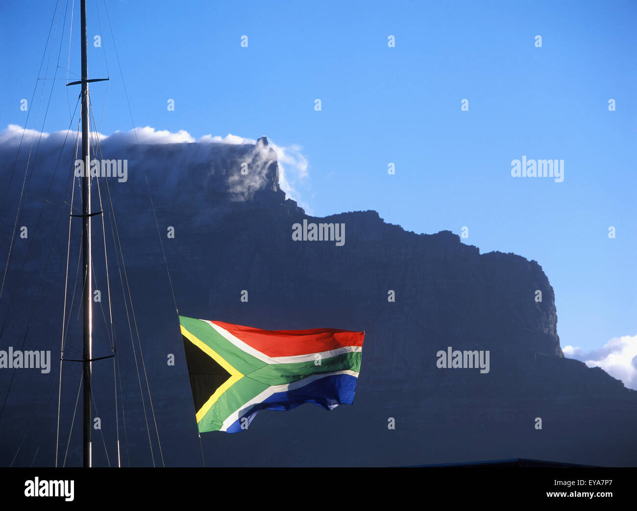South African Flag Flying Above Victoria And Albert Waterfront With Cape Town And Table Mountain Behind, South Africa. Stock Photo