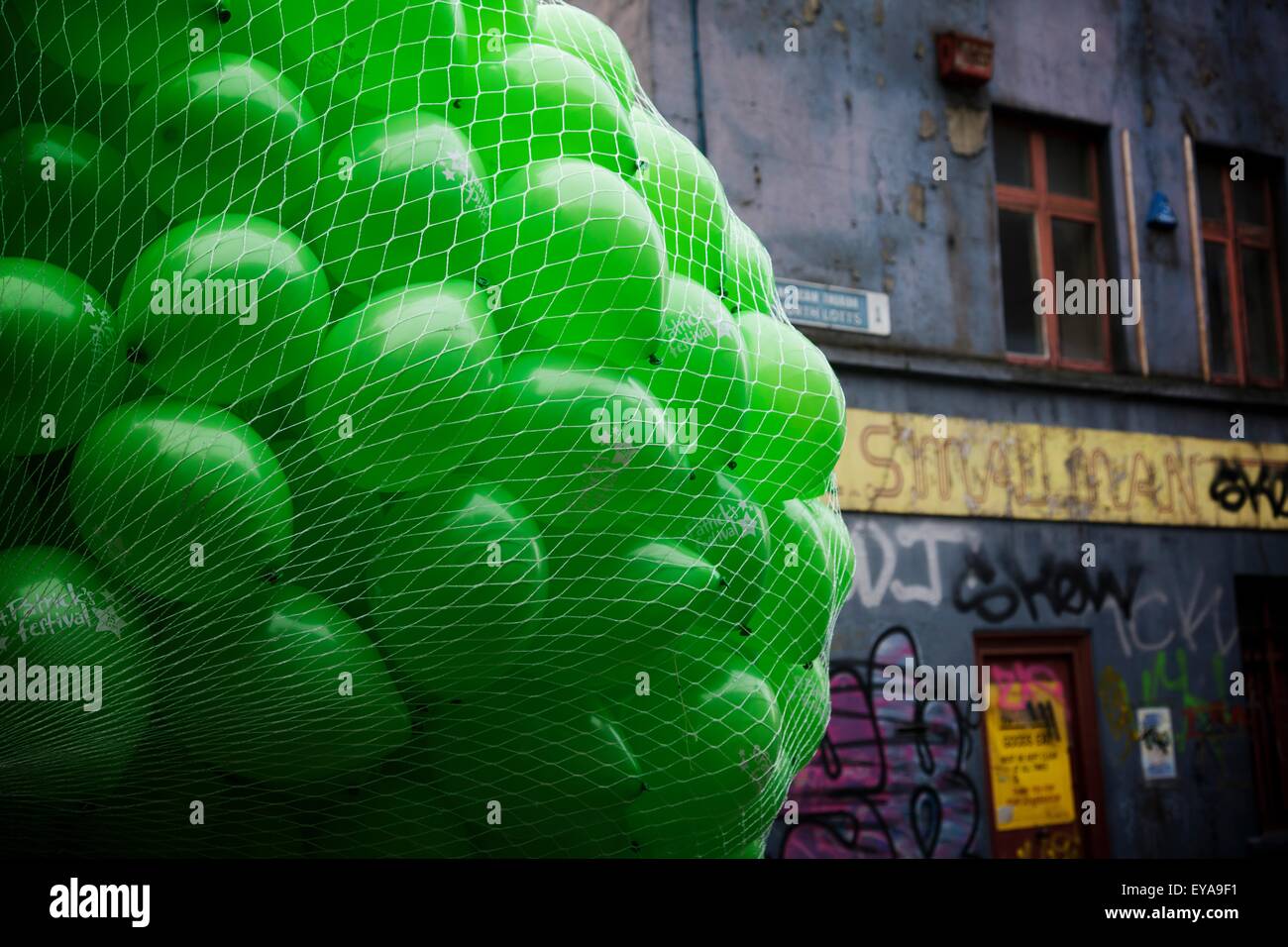 Dublin, Ireland; A Large Bundle Of Green Balloons By A Building Covered