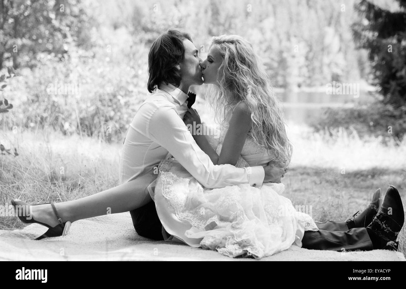 Beautiful married couple kissing on a blanket. The bride wrapping her legs  around his waist Stock Photo - Alamy