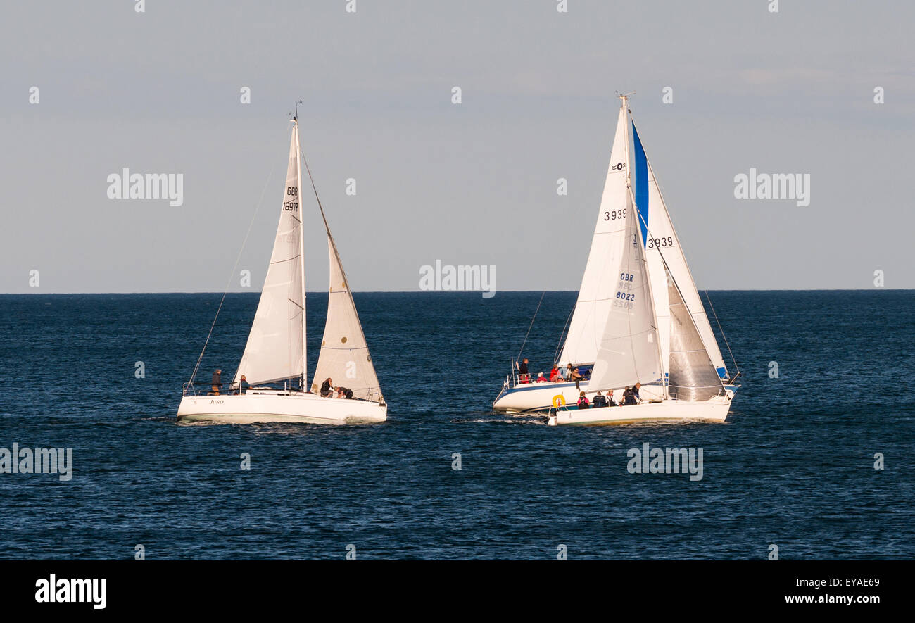 Three yachts race off the Teignmouth coast during a summer evening. Stock Photo