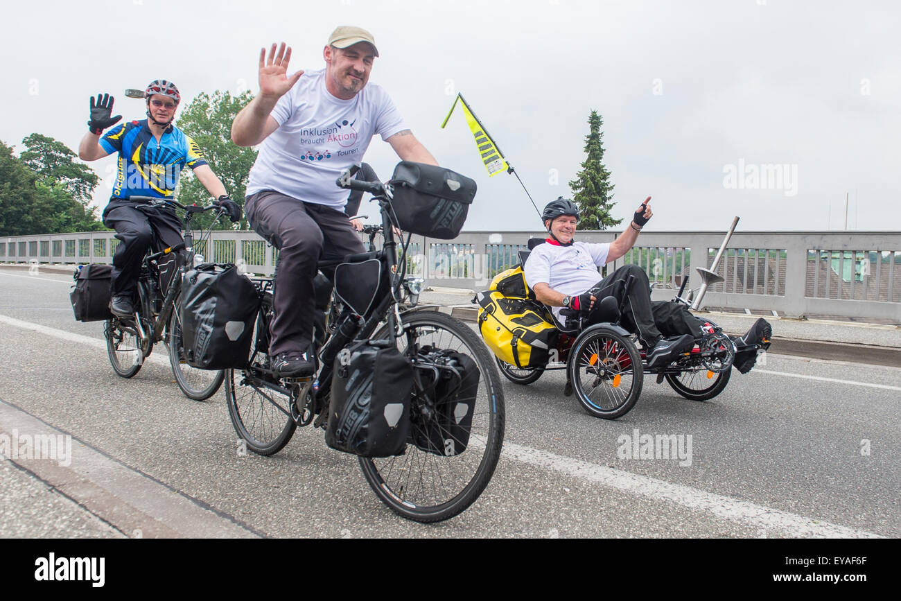 Flensburg, Germany. 25th July, 2015. Handicapped cyclists Karl Grandt (R) and Sven Marx (C) from the organization 'Inklusion braucht Aktion' (lit. Inclusion needs action) ride their bikes in Flensburg, Germany, 25 July 2015. Accompanied by numerous supporters they will cycle to Rome to promote inclusion. Photo: BENJAMIN NOLTE/dpa/Alamy Live News Stock Photo