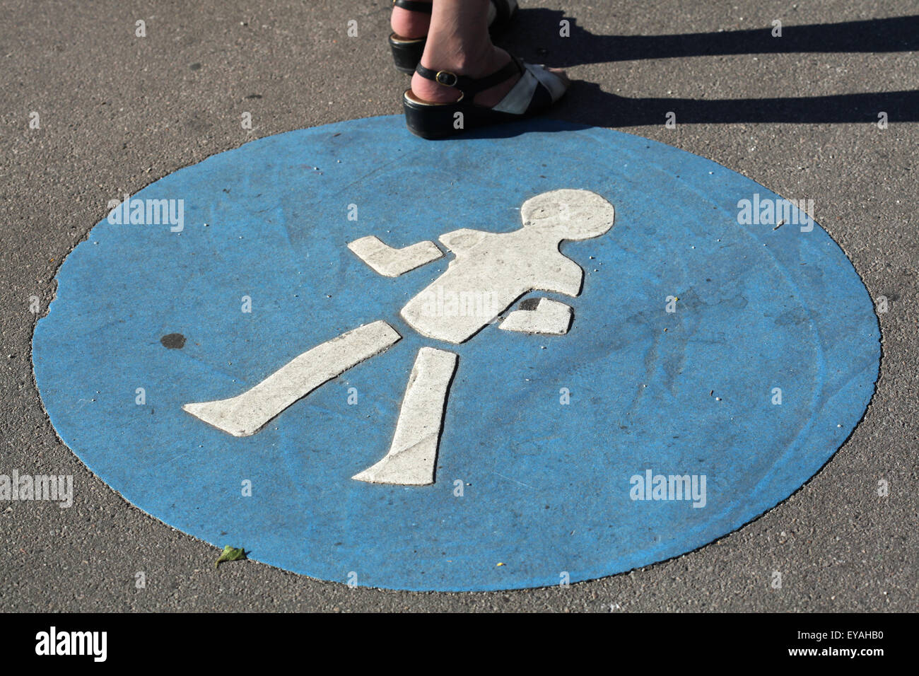 Woman stands next to a blue pedestrian walkway sign in Vienna, Austria. Stock Photo