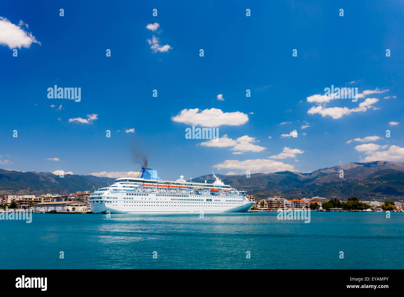 Big cruise ship anchored in port against a blue sky and clouds in Greece Stock Photo