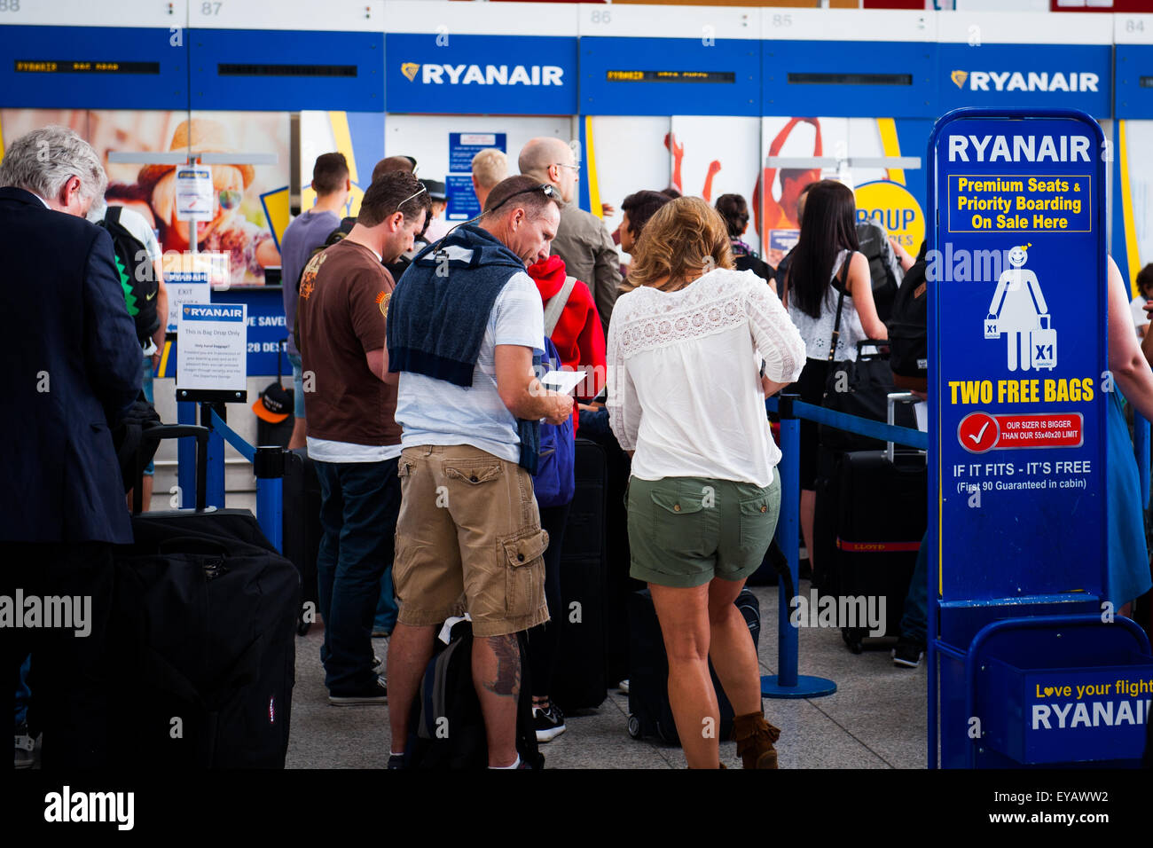 Passengers queue to drop luggage at busy Ryan Air check in desk in Stansted Airport, UK Stock Photo