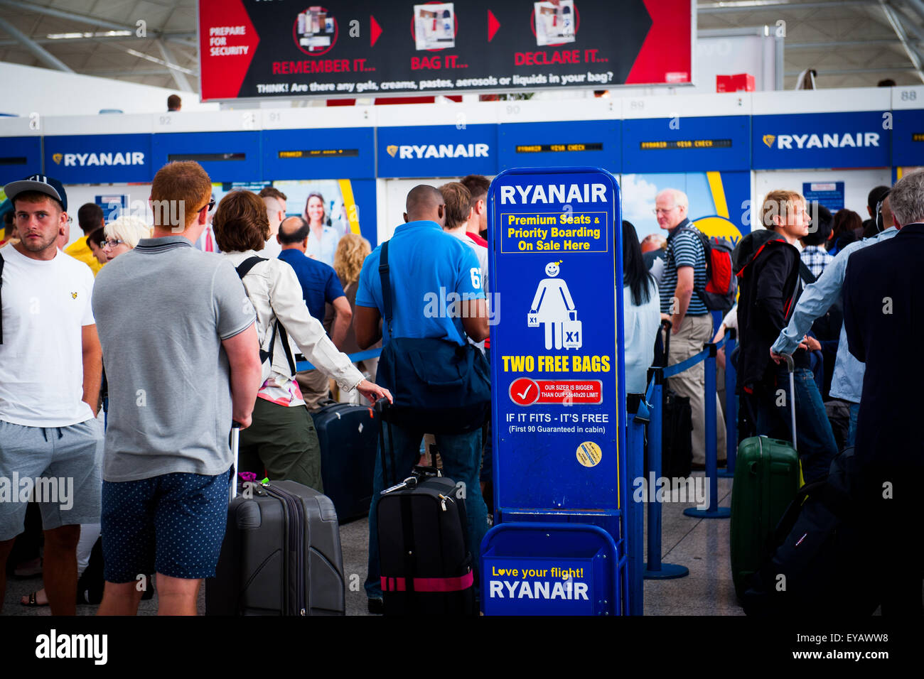 Passengers queue to drop luggage at busy Ryan Air check in desk in Stansted Airport, UK Stock Photo