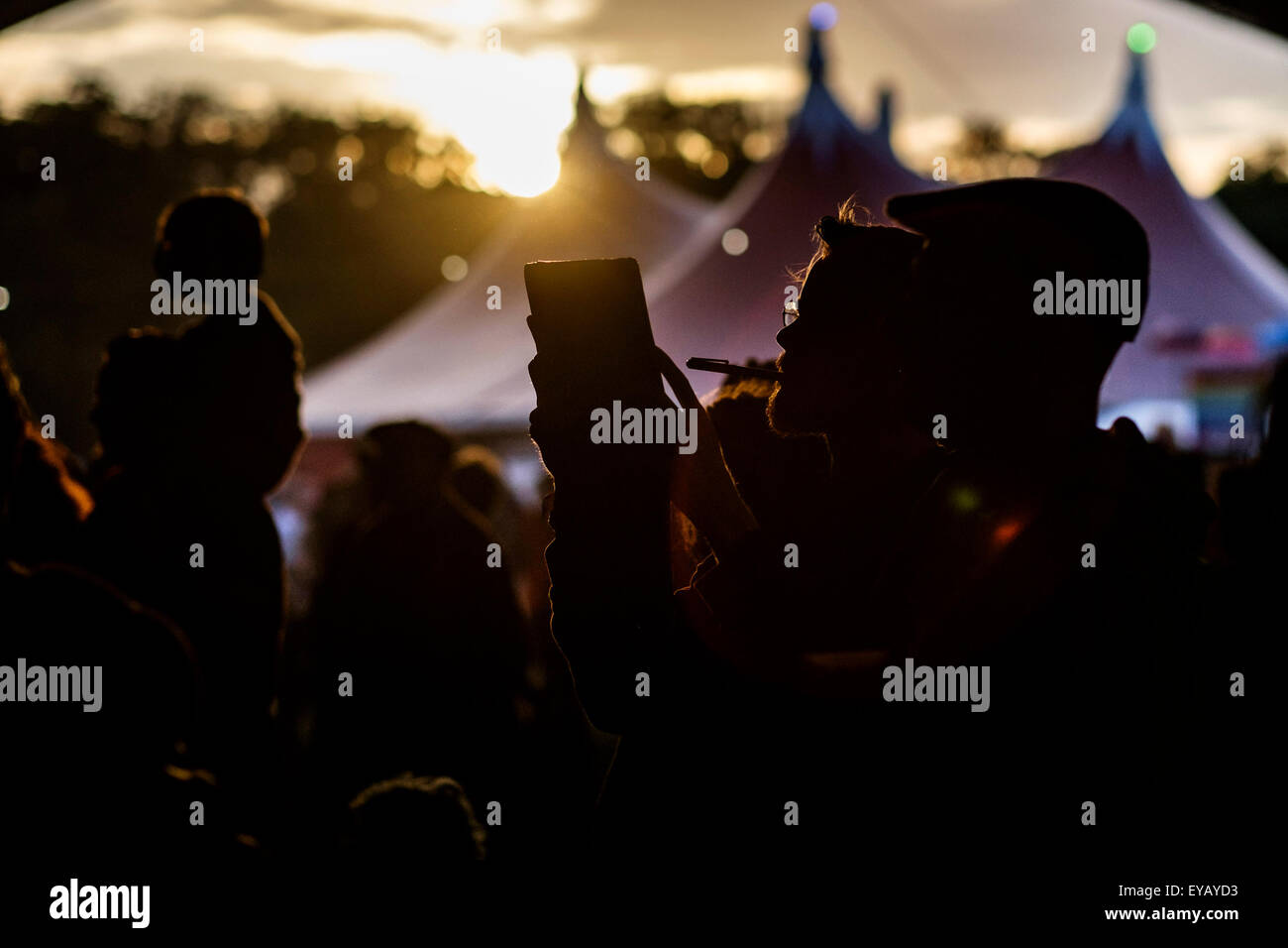 Atmosphere at WOMAD (World of Music, Arts and Dance)  Festival at Charlton Park on 25/07/2015 at Charlton Park, Malmesbury.  Festival goers relax in the Bowers & Wilkins stage tent bathed in the light of the sunset. Taking pictures on an iPad / Tablet Picture by Julie Edwards/Alamy Live News Stock Photo