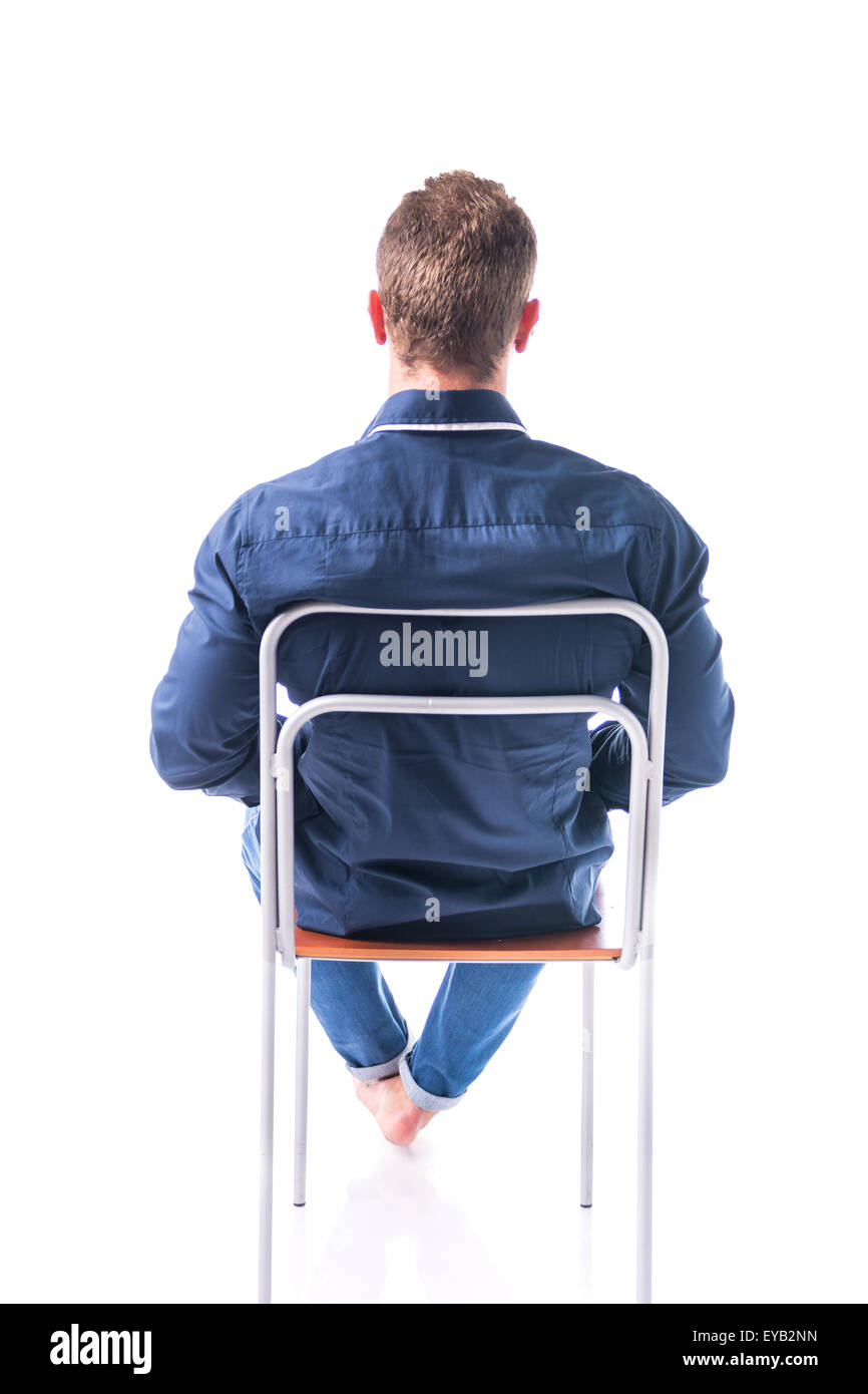 Back of barefoot young man sitting on chair, isolated on white background Stock Photo