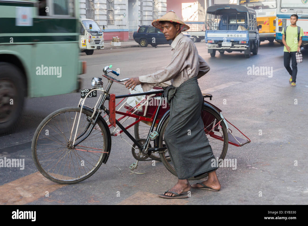 yangon, Myanmar-May 8th 2014: AA man pushes his bicycle along a street.  Bicycles are still a common sight in the city. Stock Photo