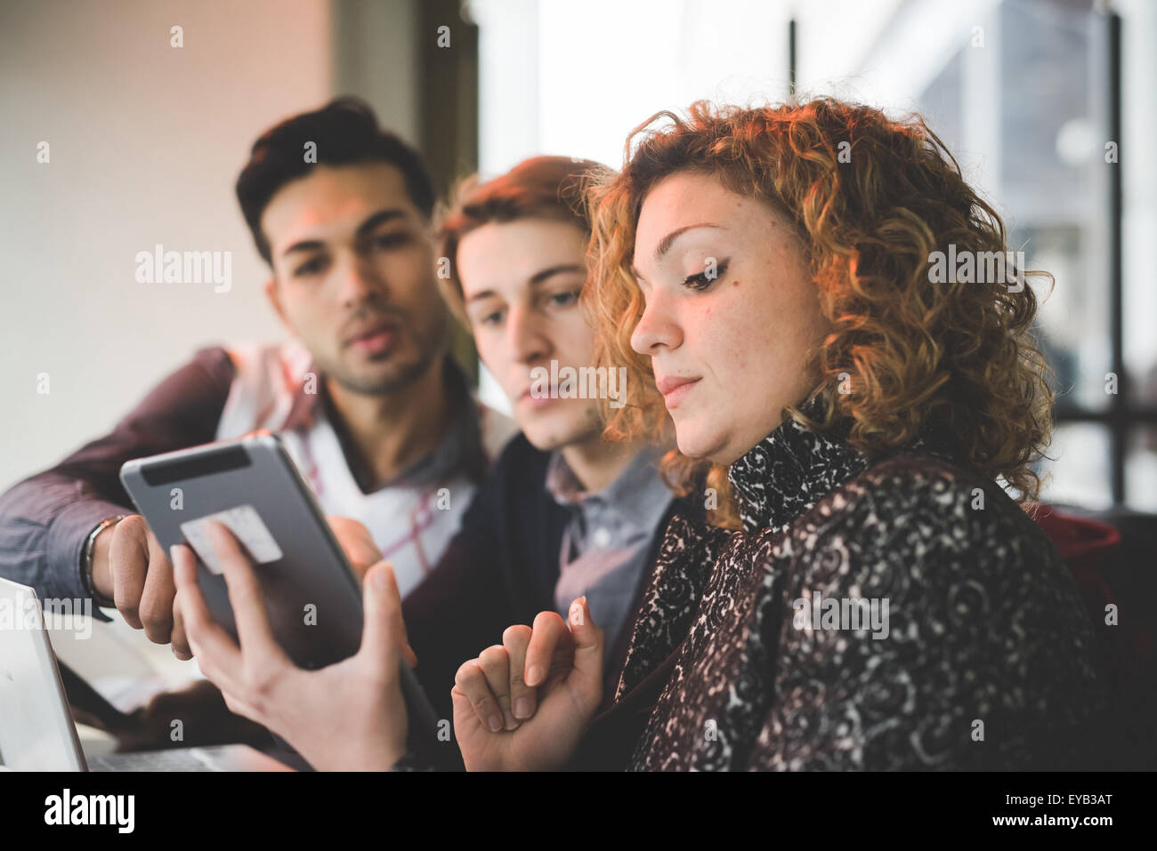 Multiracial contemporary business people working connected with technological devices like notebook and tablet at the bar indoor looking down the screen - finace, business, technology concept Stock Photo