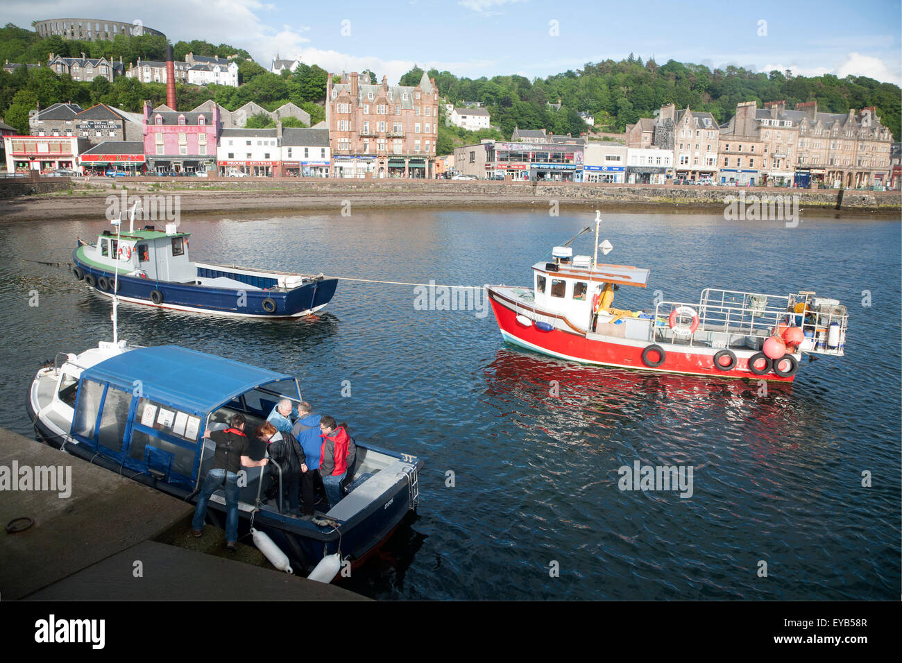 Fishing boats and small passenger foot ferry in the harbour at the town of Oban, Argyll and Bute, Scotland, UK Stock Photo