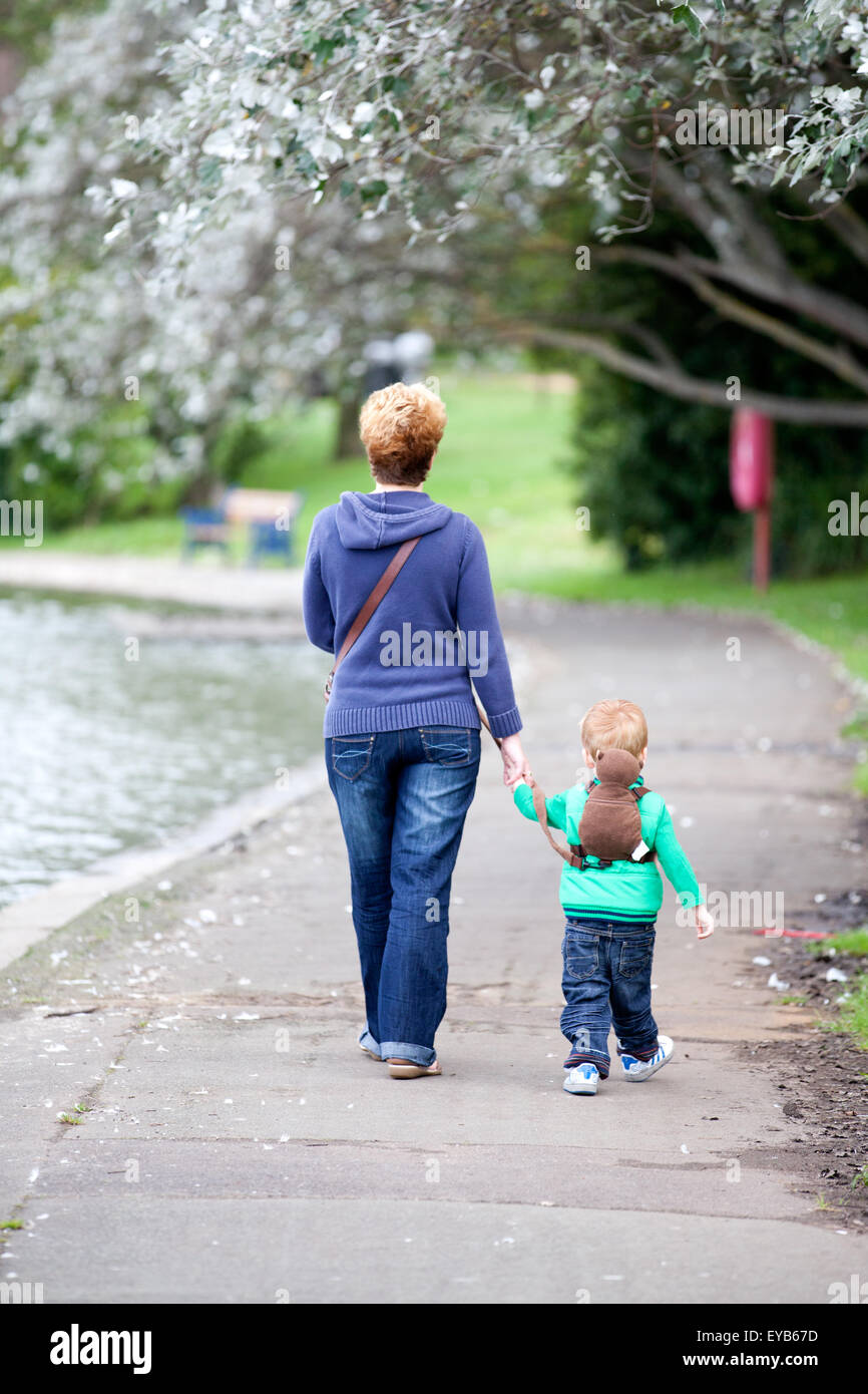 A grandmother and grandchild walking alongside a lake, hand in hand ina touching loving scene Stock Photo