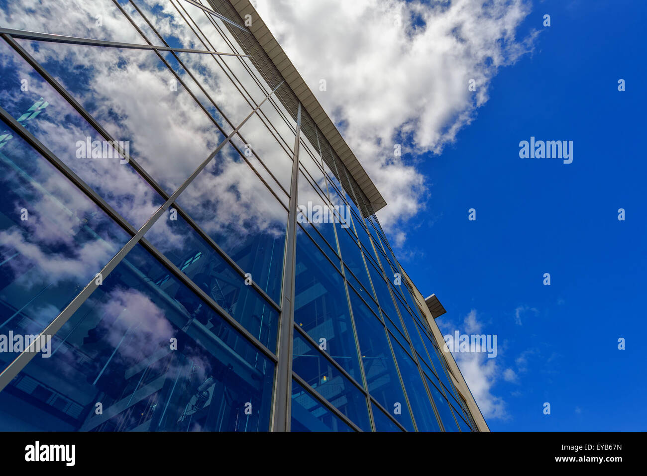 Modern Office Building with Clouds Reflecting on Glass Facade, Wide Angle Shot with Geometric Lines and Vanishing Point Stock Photo