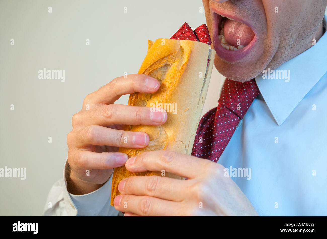 Man eating a sandwich made of his own tie. Stock Photo