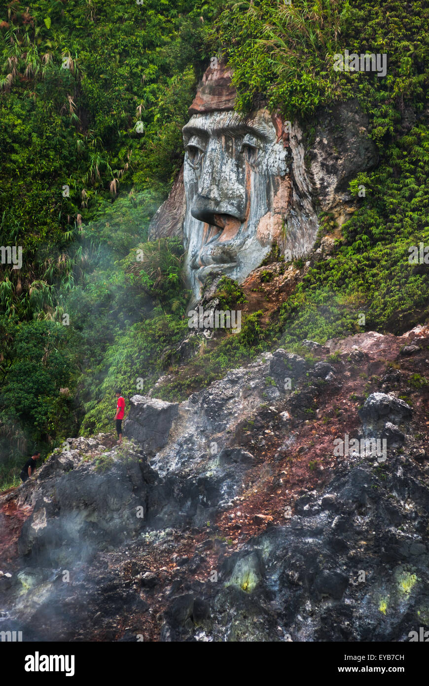 A visitor is spotted near a giant face formation illustrating the character of Toar (ancestral figure) at Bukit Kasih in North Sulawesi, Indonesia. Stock Photo