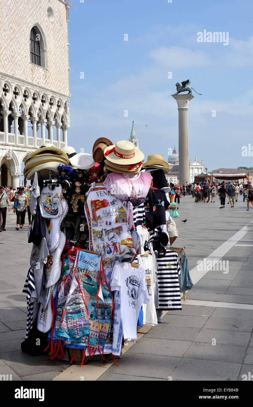 Piazzetta San Marco -Venice-Italy- tourist souvenir stall - colourful shirts hats jerseys - backdrop ducal palace - sunlight Stock Photo