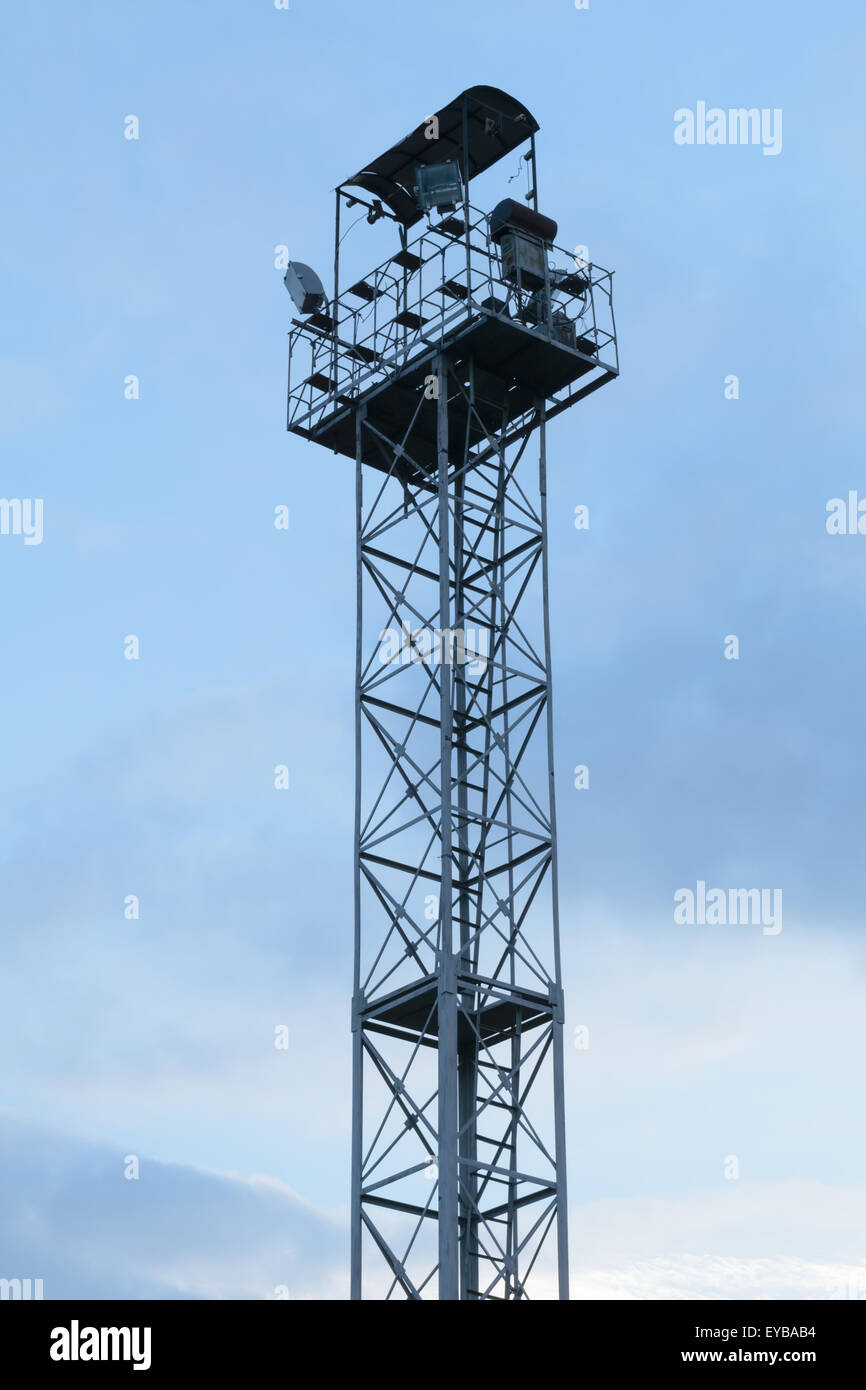 High lighting tower with observation platform at the top against a blue sky with clouds. Stock Photo