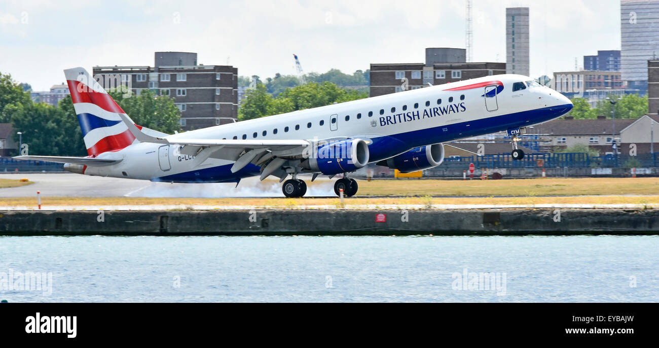 British Airways plane landing at London City Airport BA Cityflyer Embraer 190 G-LCYM burning the rubber tyres upon touchdown in London Docklands UK Stock Photo