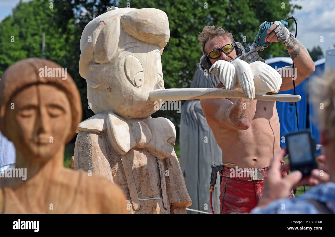Tornau, Germany. 26th July, 2015. Dirk Hantschmann from Radeberg works on a wooden sculpture depicting the children's book character Pinocchio that he cut from a poplar trunk at the 16th international wood sculpture competition in Tornau, Germany, 26 July 2015. 45 artists from Germany, England, Denmark and Lithuania have been working on their sculptures since 25 July 2015. The best results are awarded with different prizes as for example an audience award. After the competition a part of the sculptures will be exhibited for one week. Photo: HENDRIK SCHMIDT/dpa/Alamy Live News Stock Photo