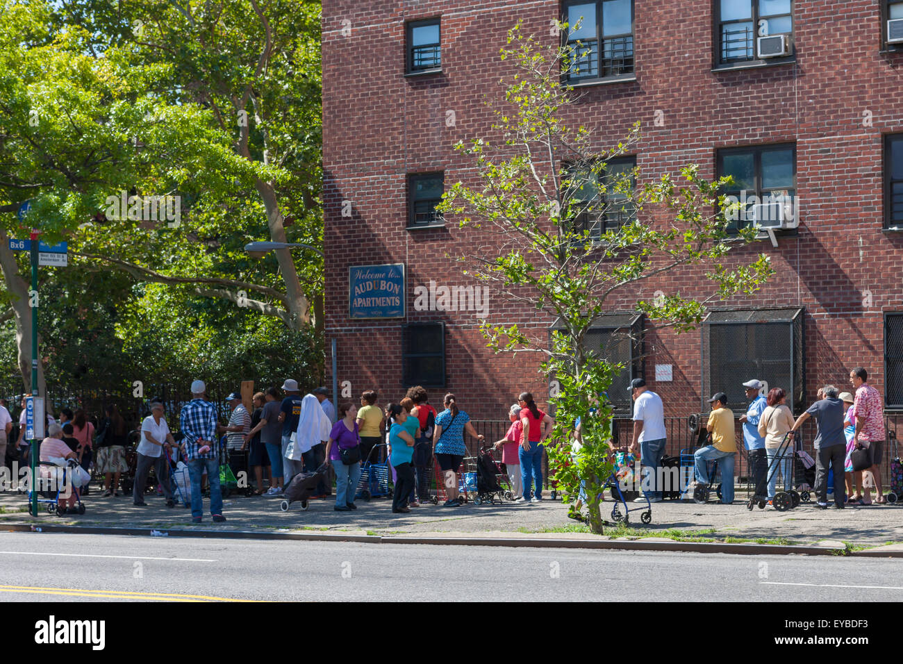 People wait in line for free food distributed by City Harvest, for the hungry, in Hamilton Heights in New York City. Stock Photo