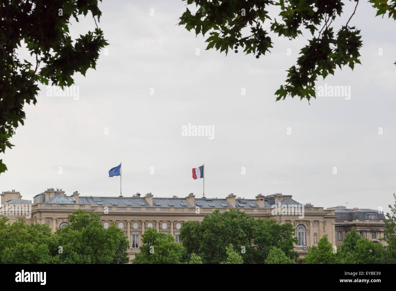The French and EU Flag on Paris Building with trees in front of the building. Stock Photo