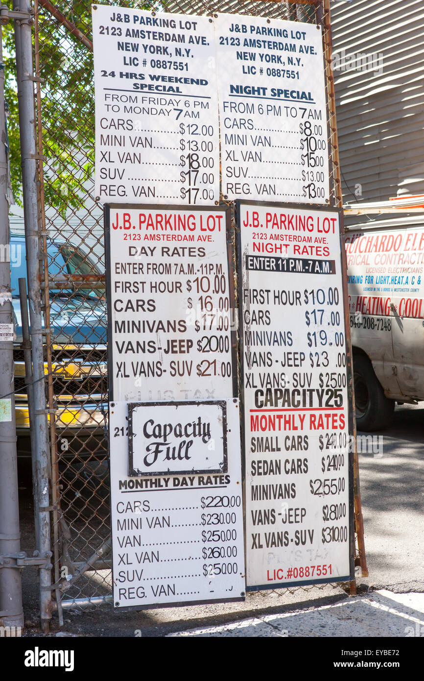 Signs on a fence gate display pricing for parking at a parking lot in New York City. Stock Photo