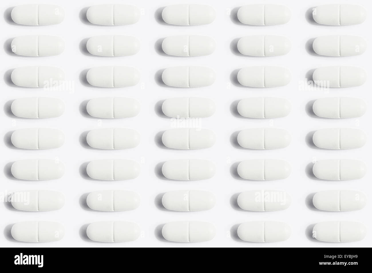 many pills / capsules arranged in row to a medical pattern background Stock Photo