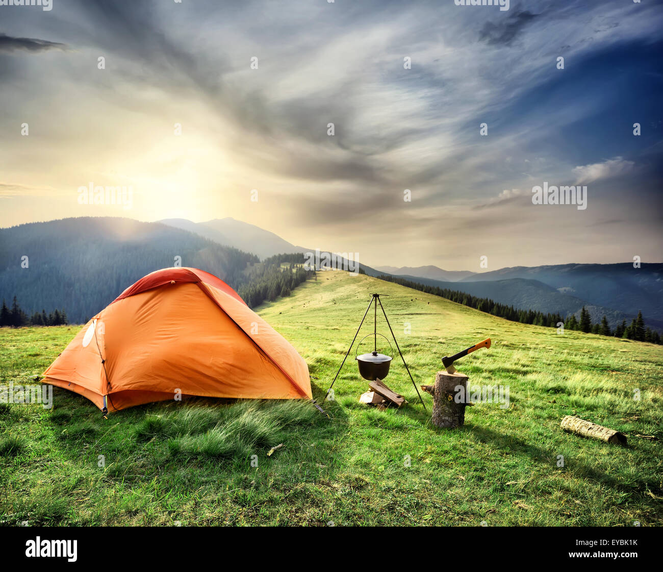 Tent on the hill beneath the mountains under dramatic sky Stock Photo