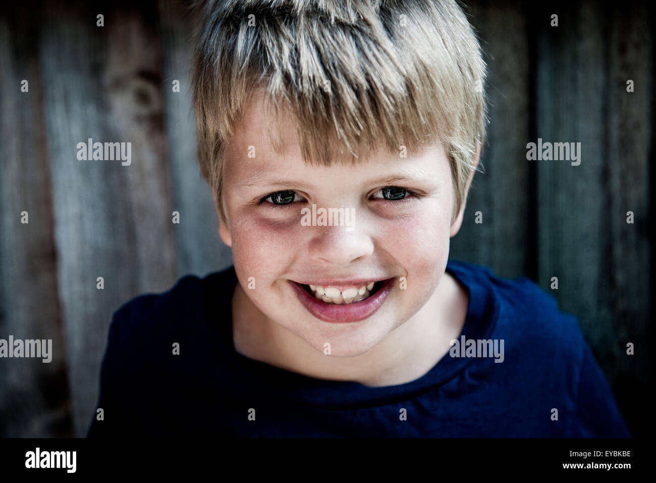 Good looking 7 8 9 year old blonde boy against a garden fence Stock Photo