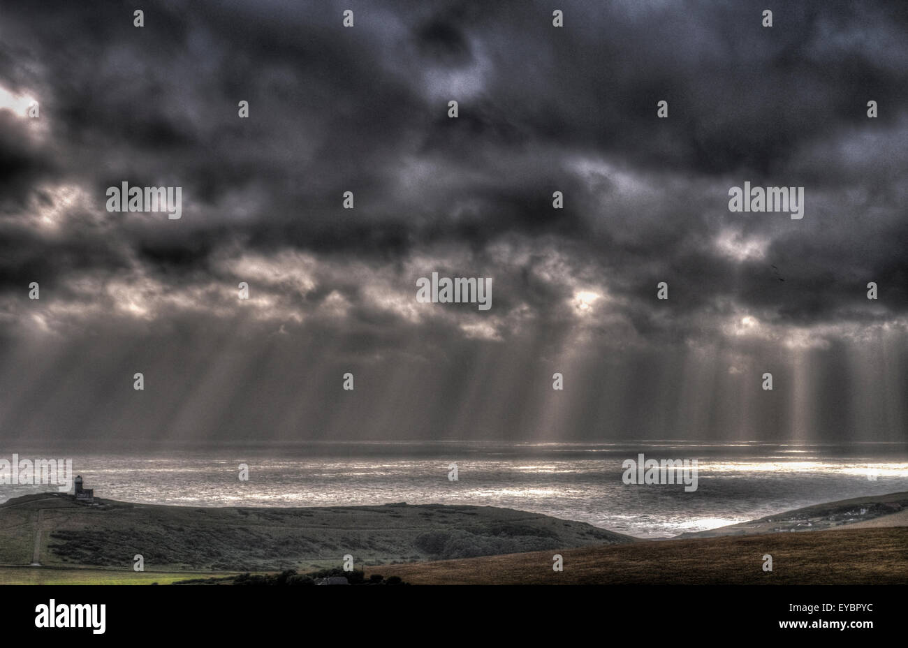 Eastbourne, East Sussex, UK. 26th July, 2015. Suns rays break through the cloud for a split second at the end of a cloudy wet windy day. Belle Tout lighthouse to left. Taken from Beachy Head. HDR Image. Stock Photo
