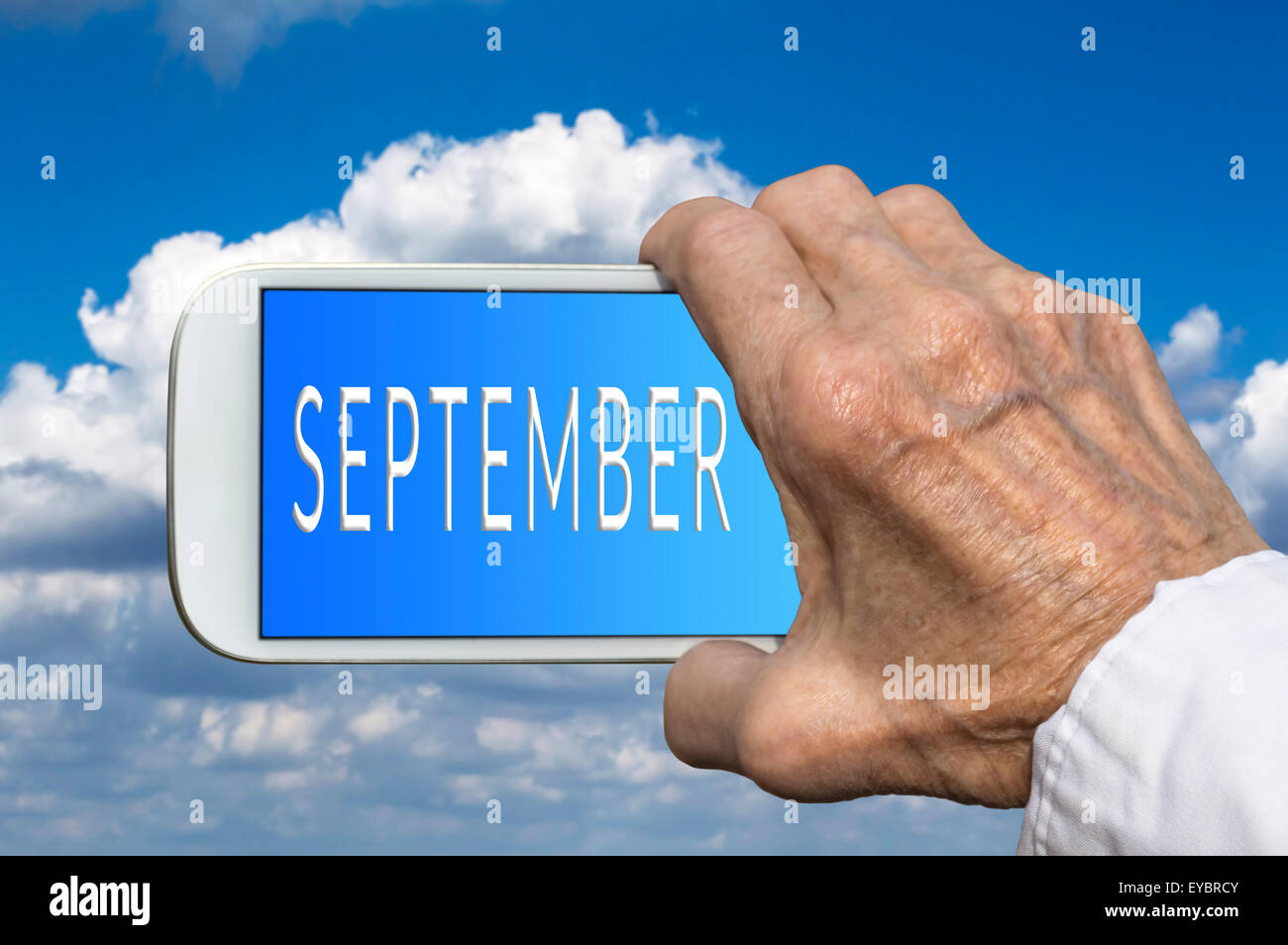 Smart phone in old hand with month of the year - September on screen. Selective focus. Stock Photo