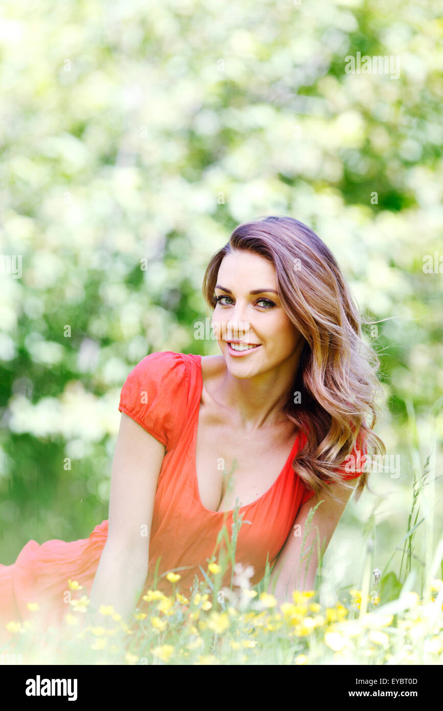 young woman in red dress sitting on grass Stock Photo - Alamy