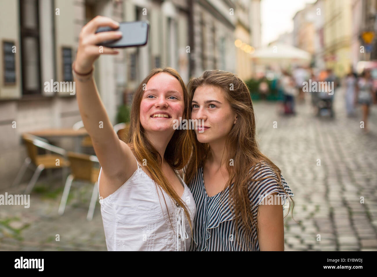 Two young cute teen girls girlfriend take a selfie on smartphone outdoors in the old town. Stock Photo