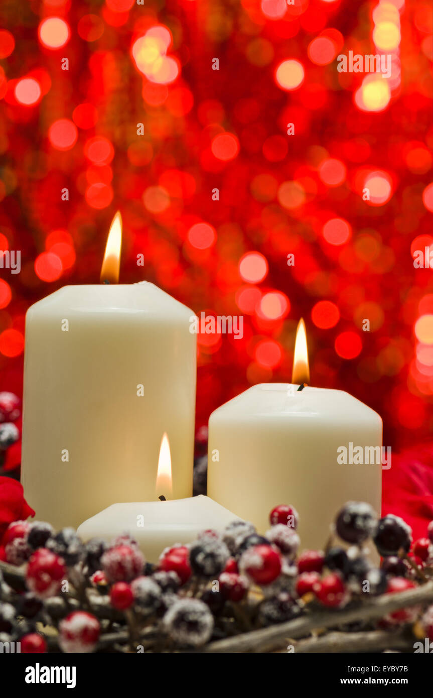 White candles in autumn winter decoration in front of a red background Stock Photo