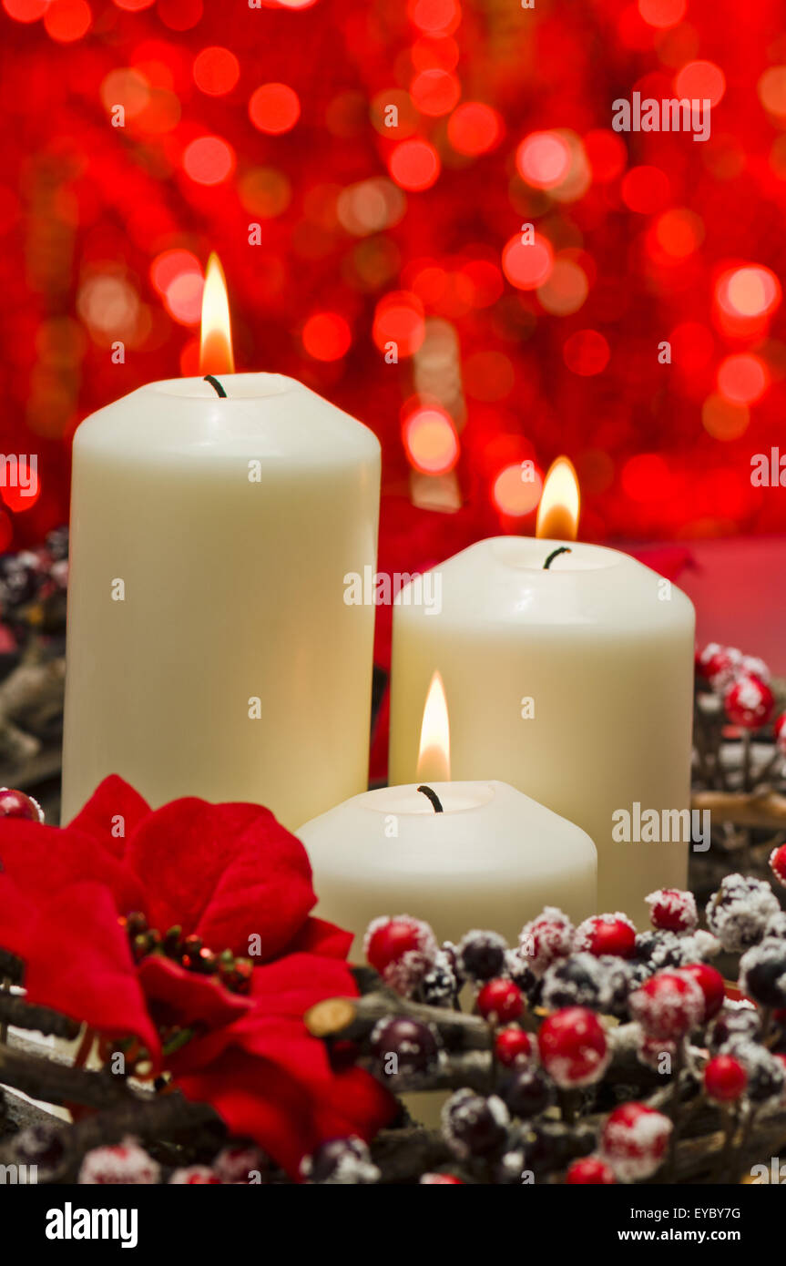 White candles in autumn winter decoration in front of a red background Stock Photo