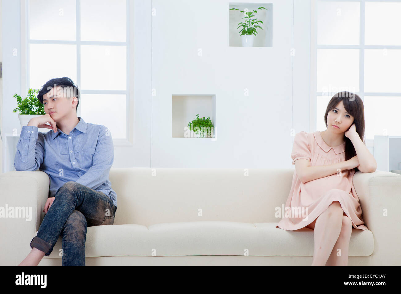 Young man and pregnant woman sitting on the sofa with bad mood, Stock Photo