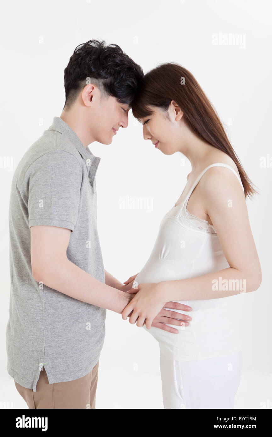 Young man and pregnant woman standing and embracing Stock Photo - Alamy