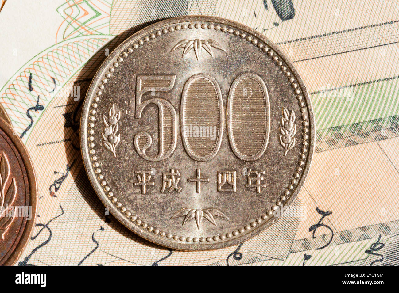 Close up of a Japanese 500 yen coin on top of a 2000 Yen Japanese banknote. Stock Photo