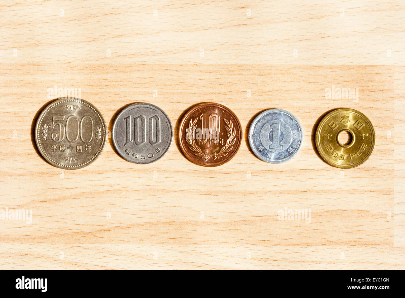 Set of current Japanese coins laid out in a row, 50b a coin with a hole in the middle, 1, 10, 100, 500 yen. Side with numbers on. Stock Photo