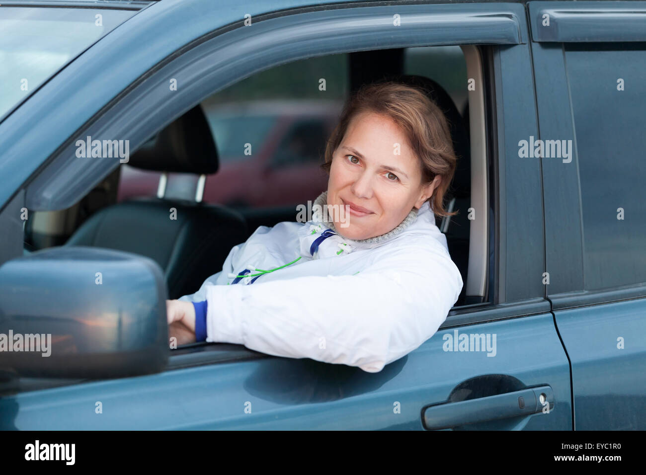 Young Caucasian woman as a driver, outdoor portrait in open car window Stock Photo
