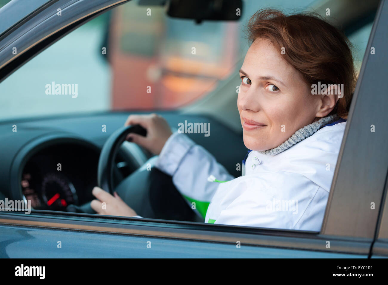 Young Caucasian woman as a driver in a car, outdoor closeup portrait Stock Photo